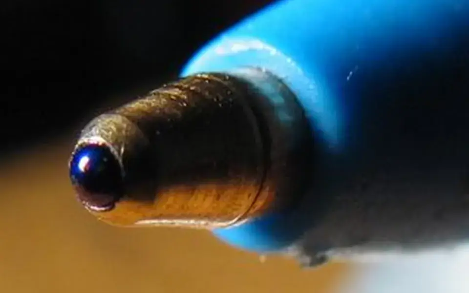 A ballpoint pen's tiny ball rolls and delivers ink