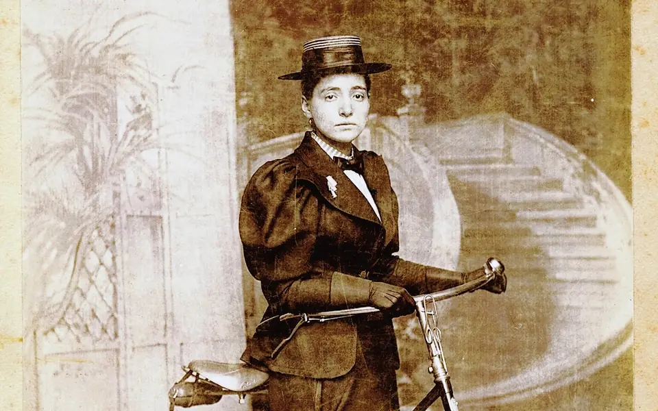 Portrait detail of Annie Londonderry wearing a hat and holding her bicycle’s handlebars, circa 1896